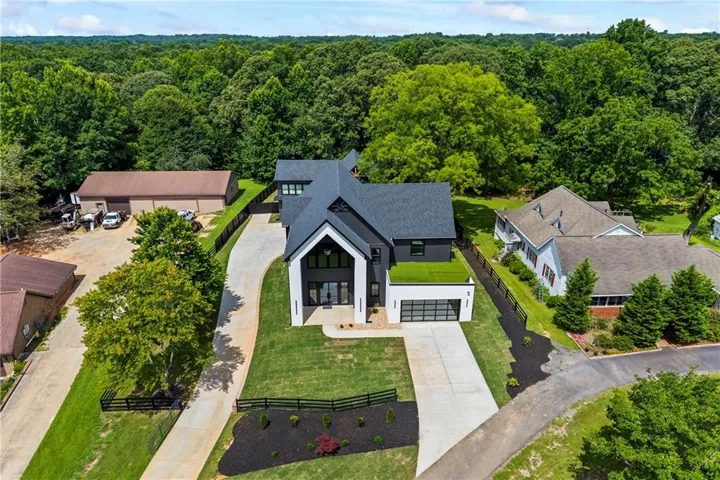Modern-style residence with a dark gray roof, white and dark gray exterior, and a two-car garage with a glass-paneled door