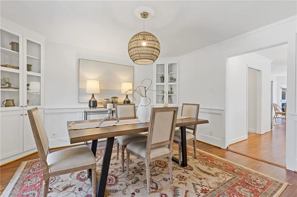 Dining area with built in shelves, ornamental molding, wainscoting, light wood-style flooring, and a decorative wall