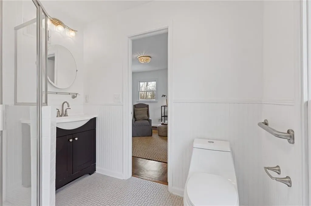 Ensuite bathroom featuring vanity, toilet, ensuite bathroom, and wainscoting