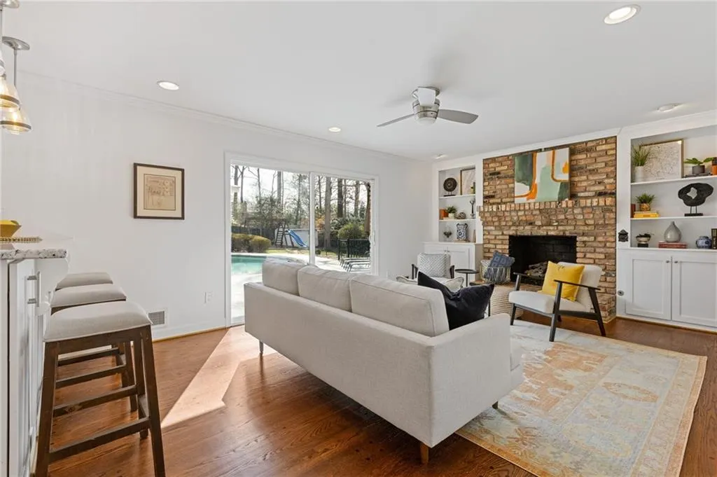 Living room featuring visible vents, a brick fireplace, crown molding, ceiling fan, and wood finished floors