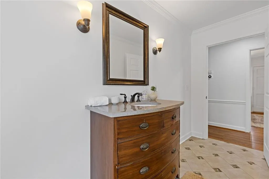 Bathroom featuring vanity, crown molding, and baseboards