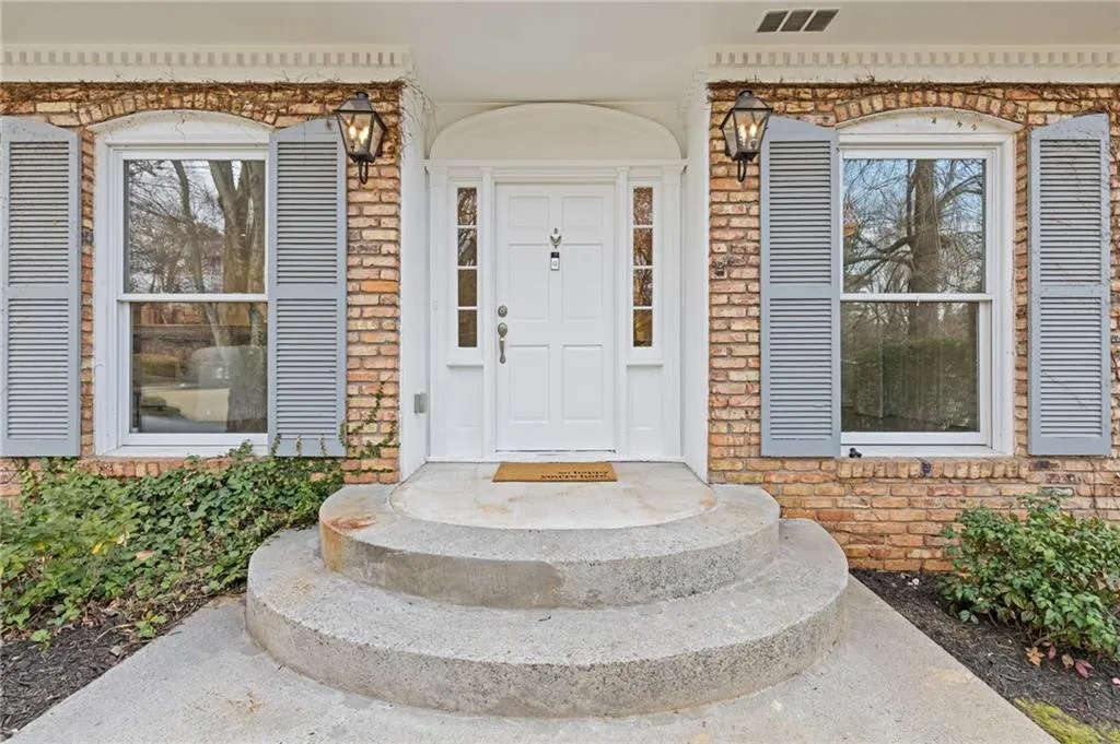 Entrance to property with visible vents and brick siding