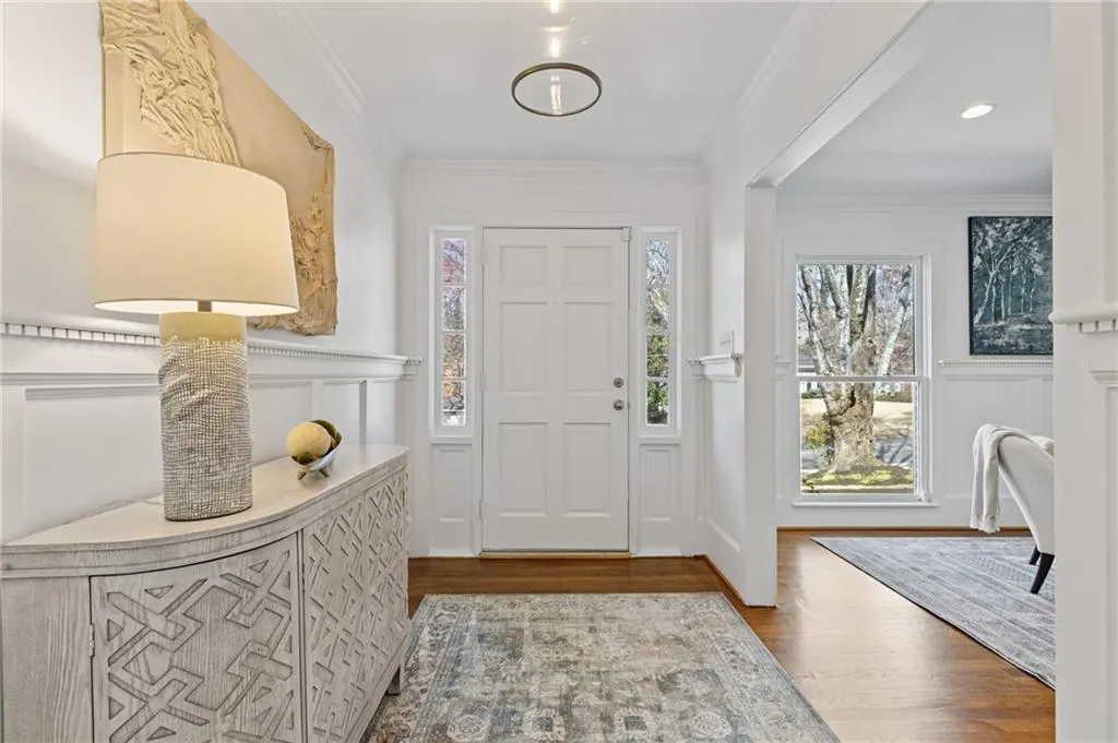Entrance foyer with a wainscoted wall, wood finished floors, crown molding, and a decorative wall