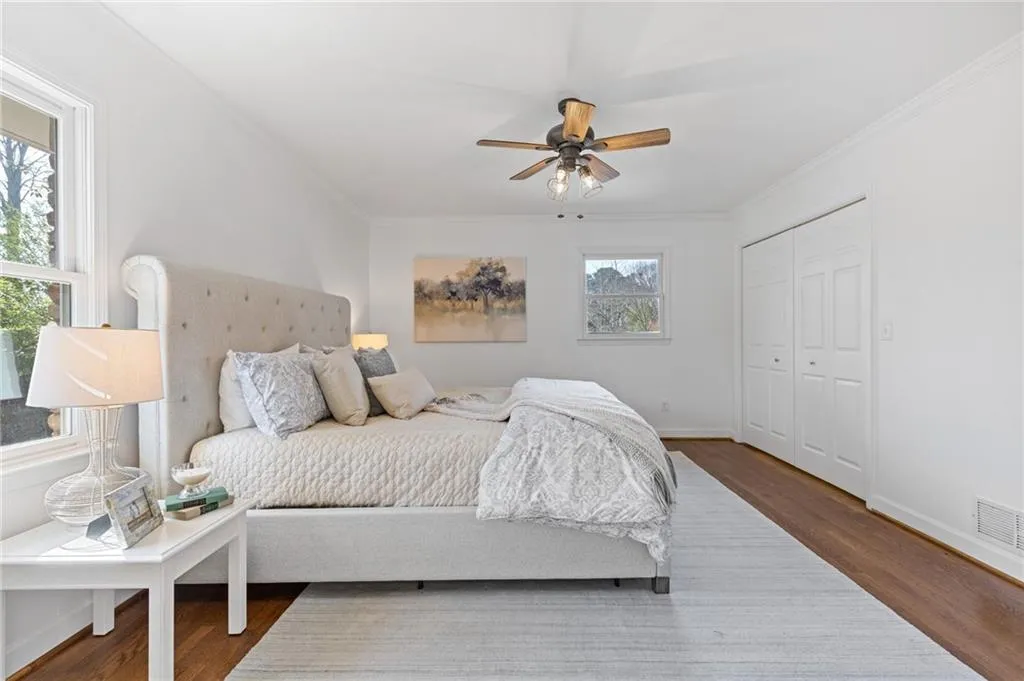 Bedroom with visible vents, baseboards, wood finished floors, and ornamental molding