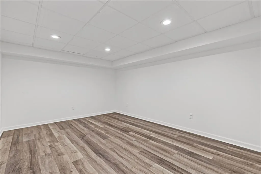 Unfurnished room featuring recessed lighting, a paneled ceiling, baseboards, and wood finished floors