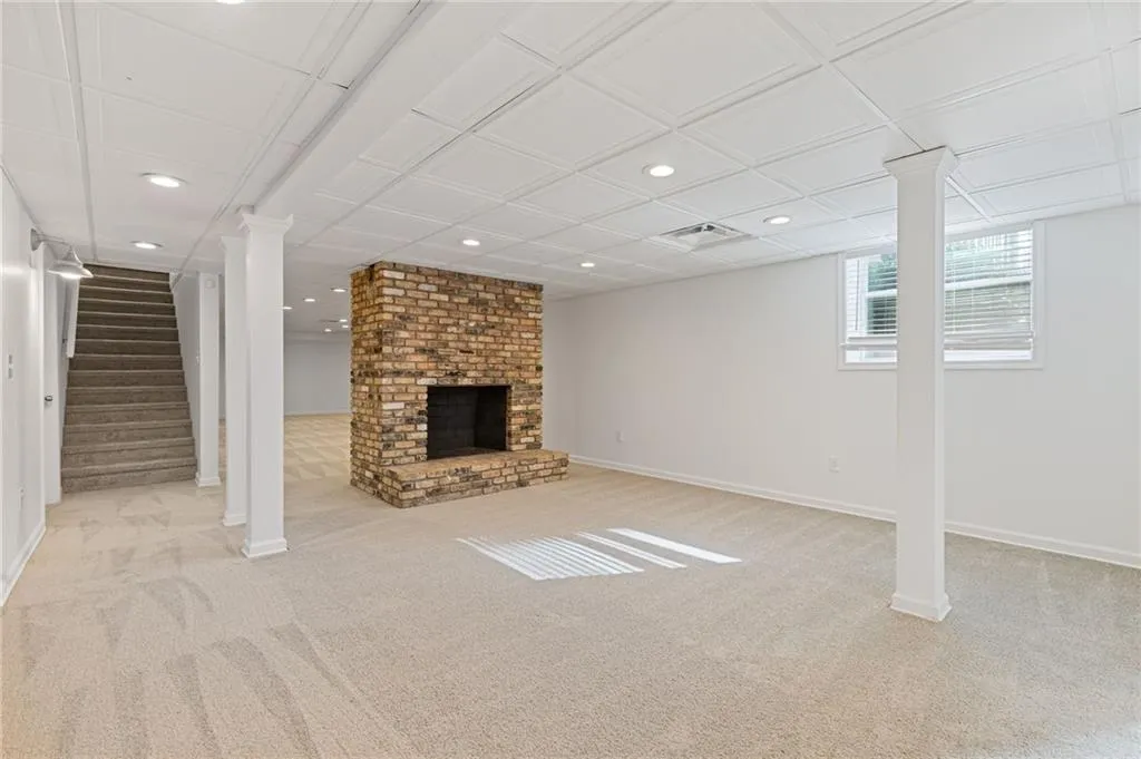 Below grade area featuring carpet, visible vents, baseboards, a fireplace, and recessed lighting