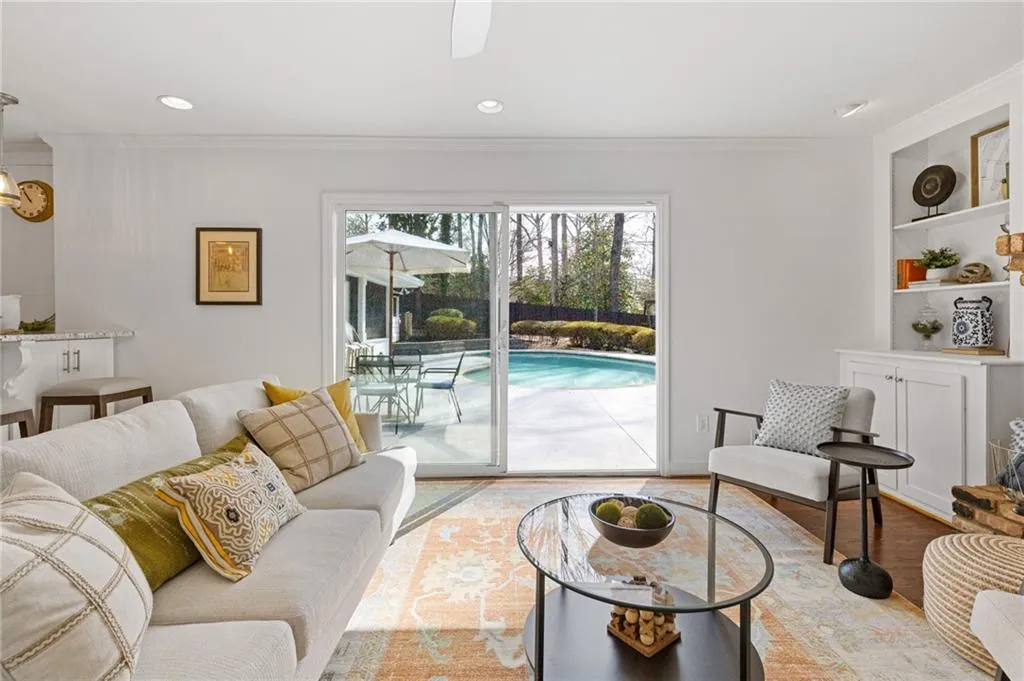 Living room with built in features, wood finished floors, recessed lighting, and ornamental molding