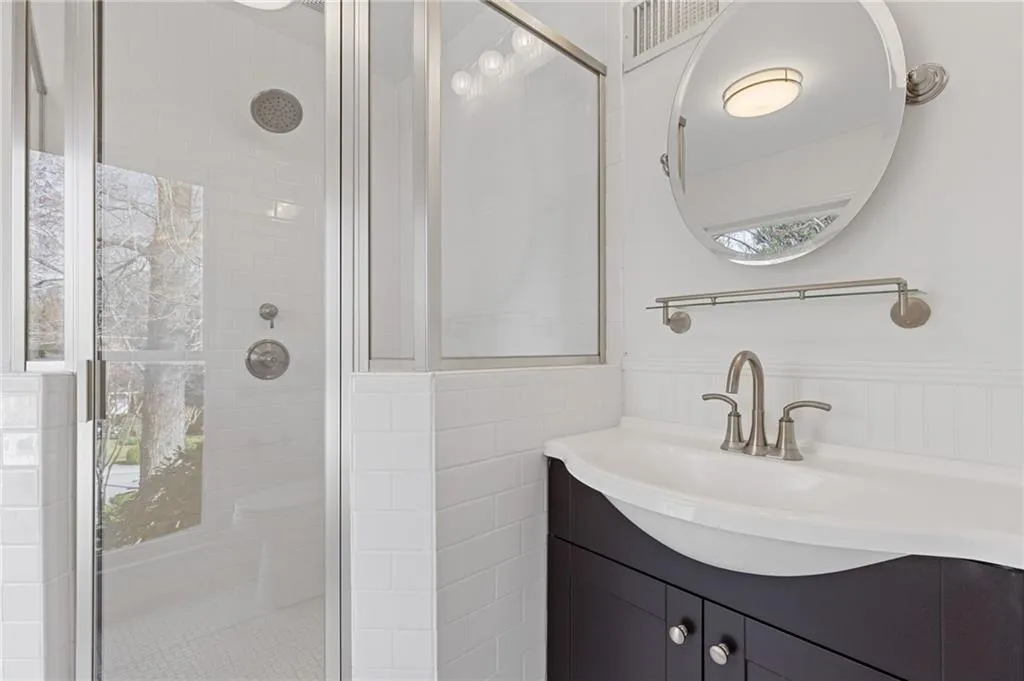 Bathroom featuring vanity, visible vents, a wainscoted wall, a shower stall, and tile walls