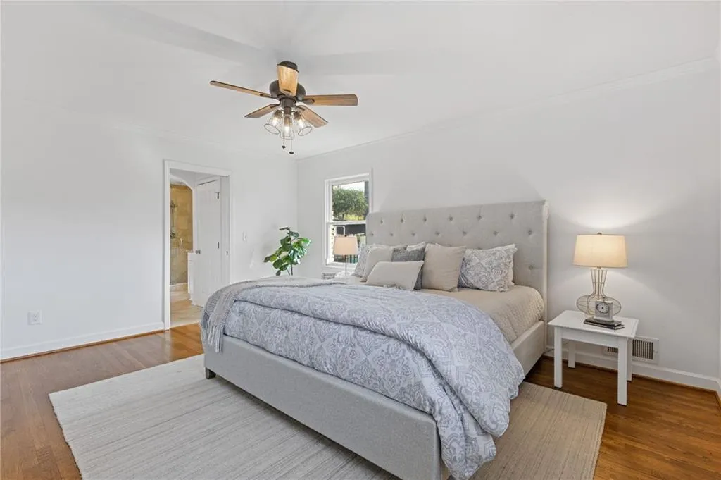 Bedroom with visible vents, connected bathroom, ceiling fan, baseboards, and wood finished floors
