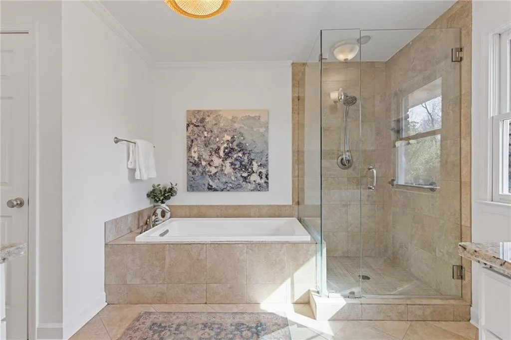 Full bath featuring tile patterned flooring, ornamental molding, a wealth of natural light, a stall shower, and a bath
