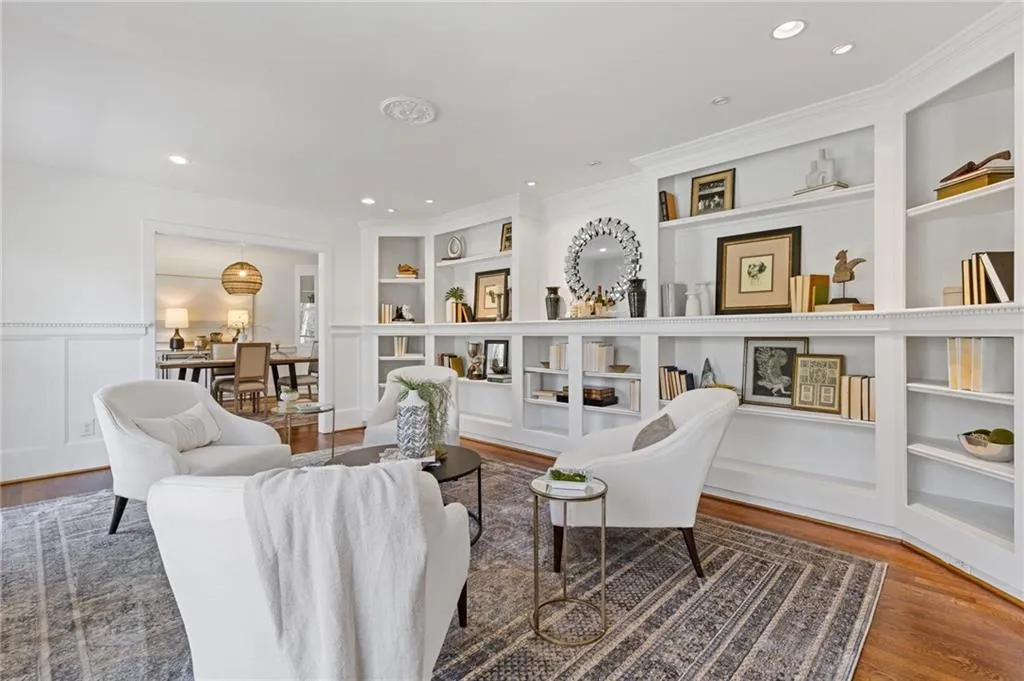 Living room with built in features, wood finished floors, recessed lighting, wainscoting, and a decorative wall