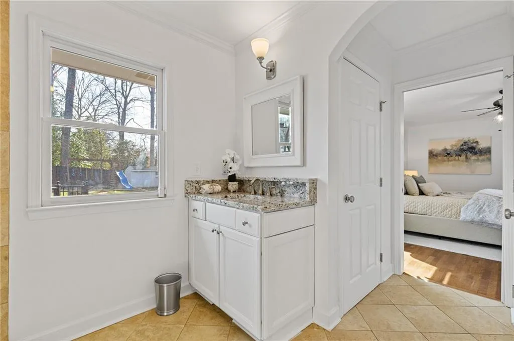 Bathroom with tile patterned flooring, ceiling fan, baseboards, ornamental molding, and vanity