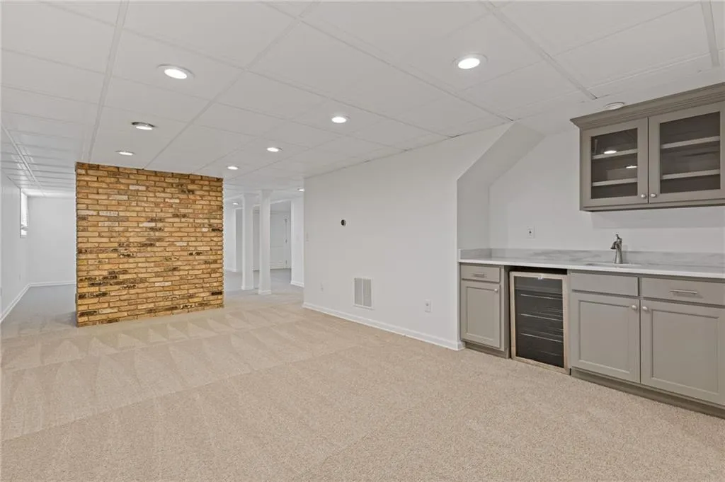 Bar with wine cooler, light colored carpet, indoor wet bar, and baseboards
