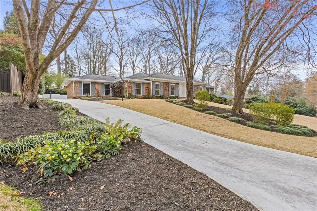 View of front facade with concrete driveway, fence, brick siding, and a front yard