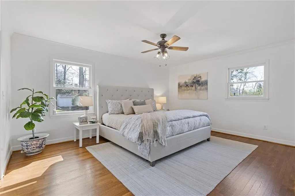 Bedroom featuring baseboards, multiple windows, wood finished floors, and a ceiling fan