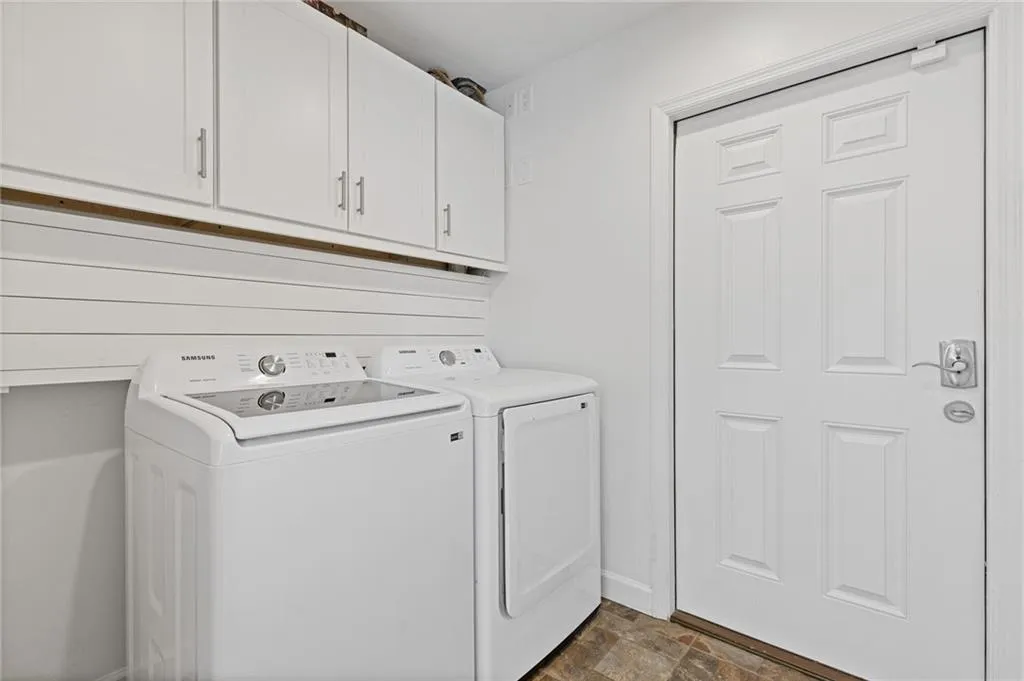 Clothes washing area featuring cabinet space, stone finish flooring, independent washer and dryer, and baseboards