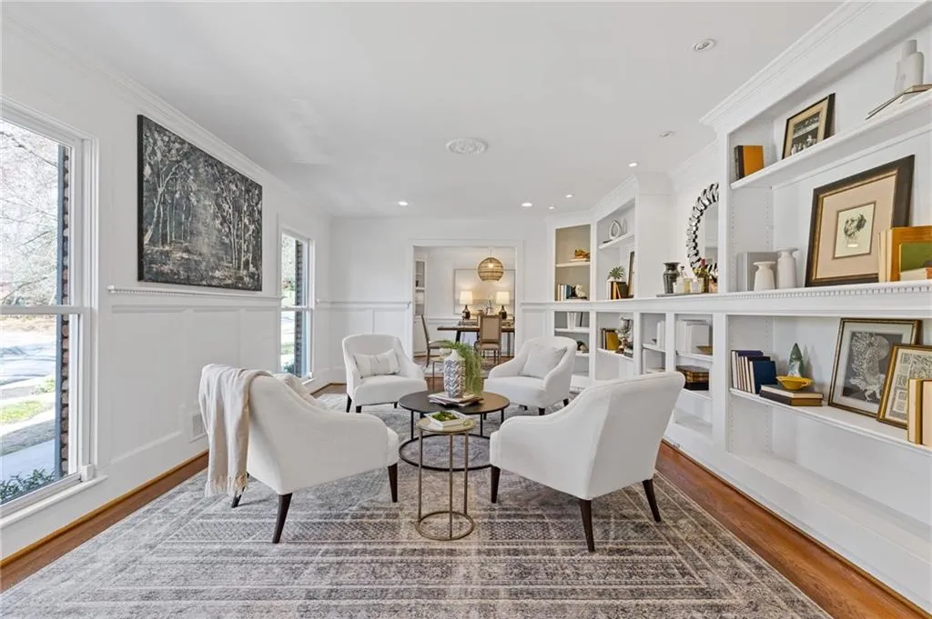 Sitting room with built in features, wainscoting, crown molding, and wood finished floors