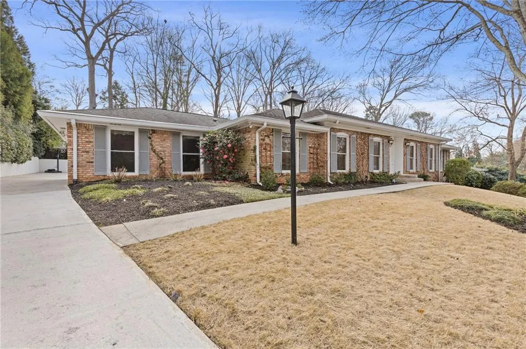 Ranch-style home featuring brick siding, a front lawn, and fence
