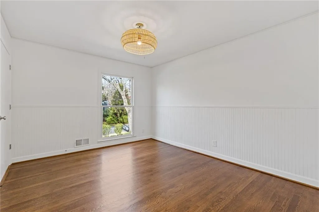 Spare room with visible vents, a wainscoted wall, and wood finished floors