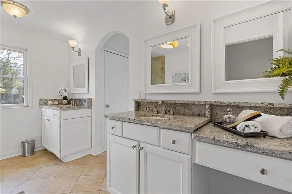 Full bathroom with baseboards, two vanities, a sink, tile patterned flooring, and crown molding