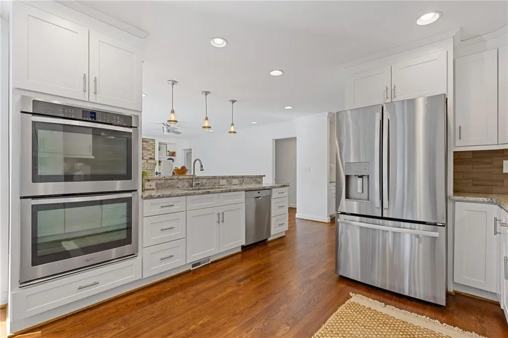 Kitchen with a sink, stainless steel appliances, a peninsula, and white cabinetry