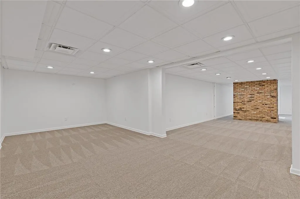 Finished below grade area with light carpet, visible vents, recessed lighting, and baseboards