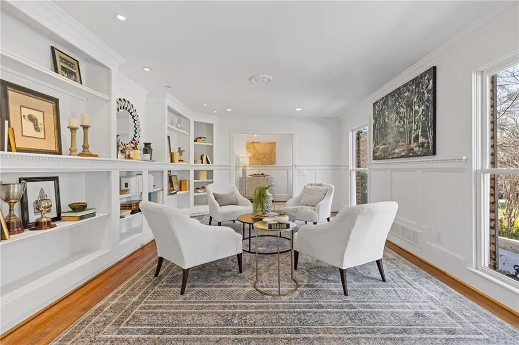Living area featuring built in features, wood finished floors, visible vents, crown molding, and a decorative wall