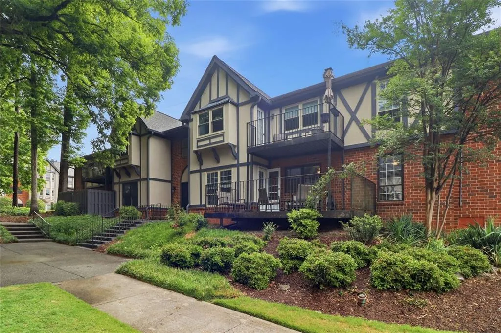 Tudor-style exterior with brick and stucco facade, featuring exposed timber framing, a private balcony, and a ground-level patio