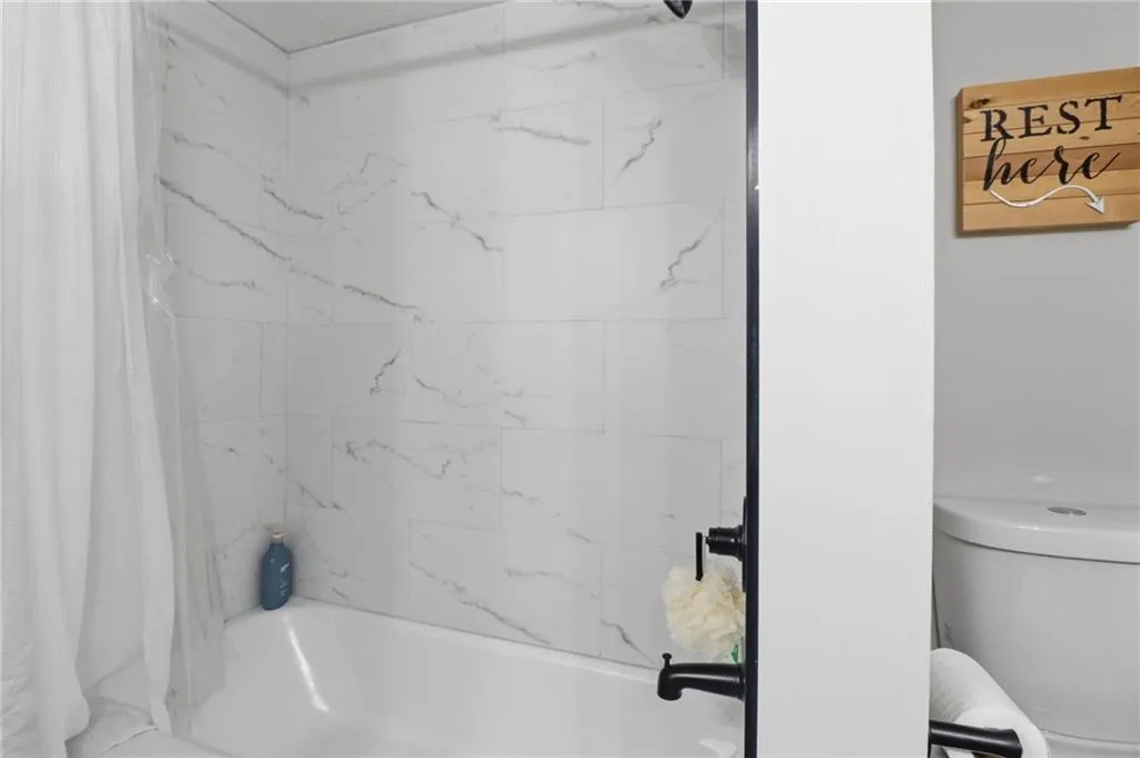 Bathtub with white subway tile surround featuring gray veining