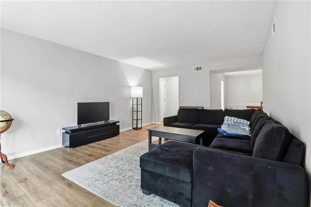 Spacious living area featuring light wood-finish flooring, neutral wall paint, and recessed ceiling vents