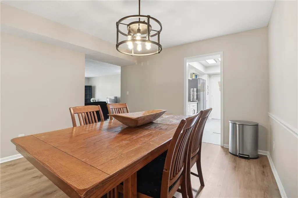 Dining area featuring wood-finish flooring, a contemporary circular chandelier, and direct access to the kitchen
