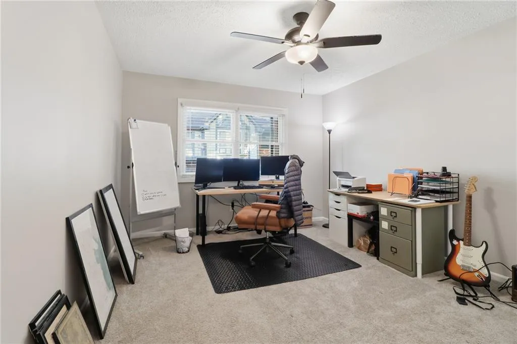 Carpeted room with a ceiling fan light fixture and neutral-toned walls