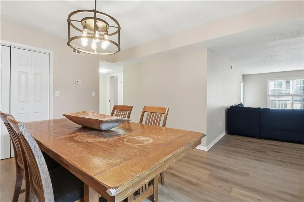 Dining area featuring wood-finish flooring, a contemporary circular chandelier, and light neutral wall paint