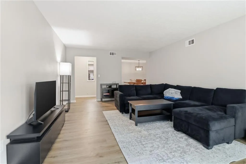 Spacious living area featuring light wood-finish flooring, light gray wall tones, and a recessed doorway