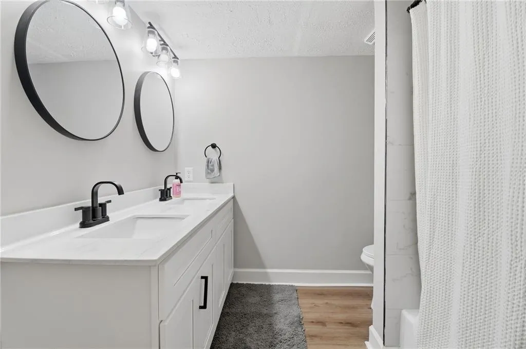 Dual vanity with white shaker-style cabinetry, matte black hardware, and two round mirrors