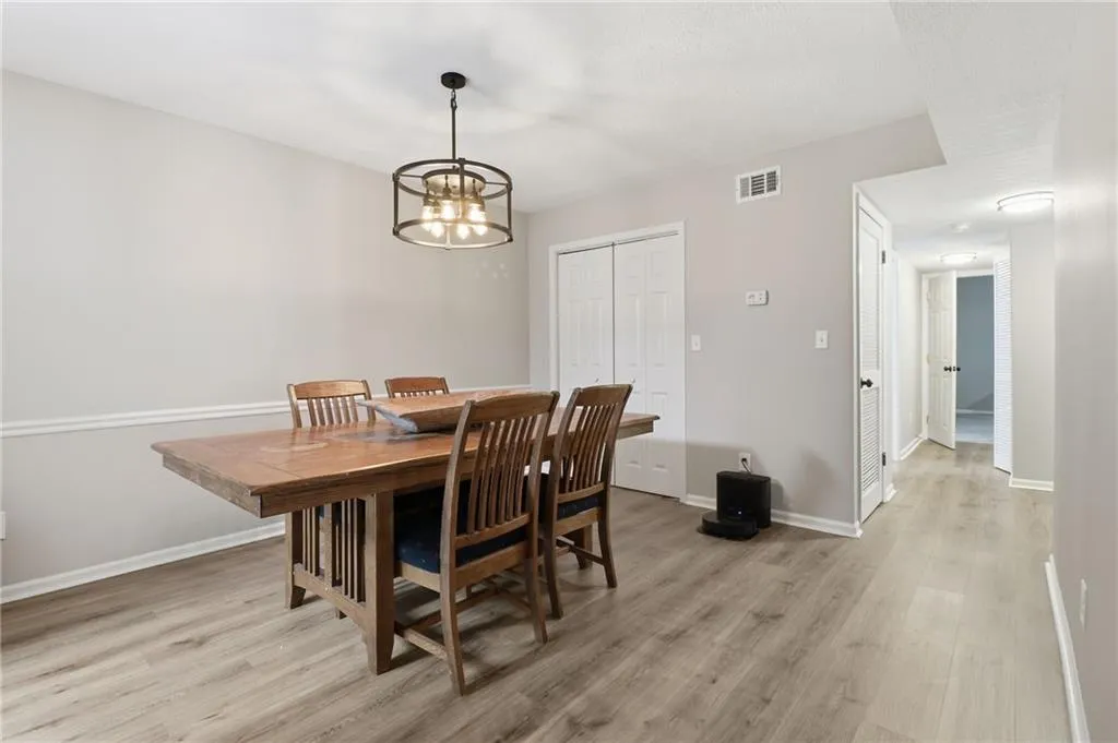 Dining area featuring a contemporary chandelier, neutral wall paint, white baseboards, and wood-finish flooring