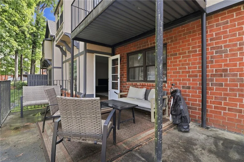 Covered patio space featuring a red brick exterior wall and an exterior door with louvered blinds