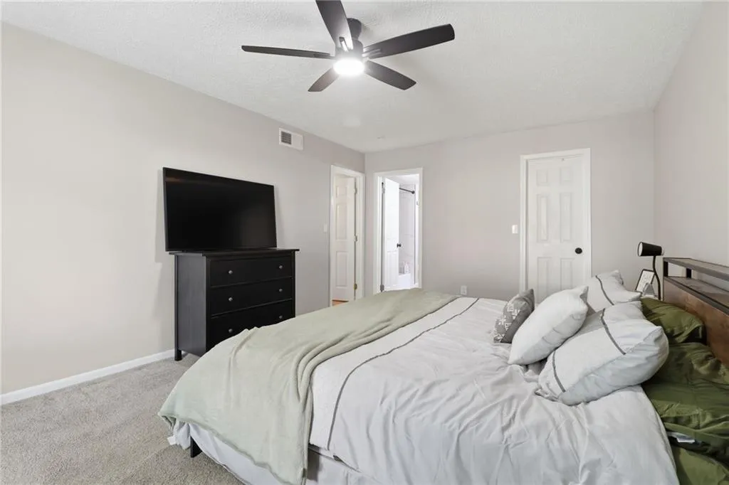 Carpeted room with a ceiling fan, light gray wall paint, white trim, and a paneled door