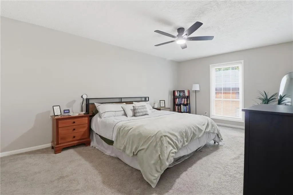 Spacious carpeted room featuring a ceiling fan, a single window with blinds, and neutral wall tones