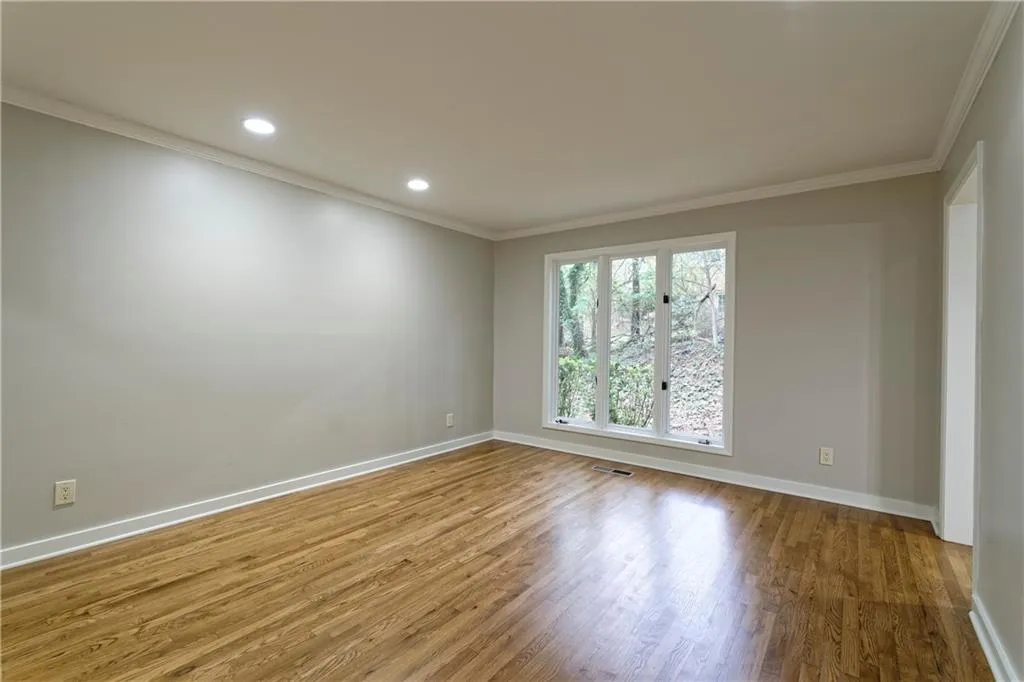 Spare room with wood finished floors, crown molding, baseboards, and recessed lighting