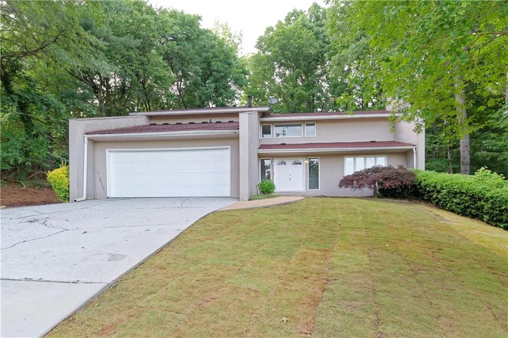 Mid-century modern home featuring stucco siding, a garage, driveway, and a front yard