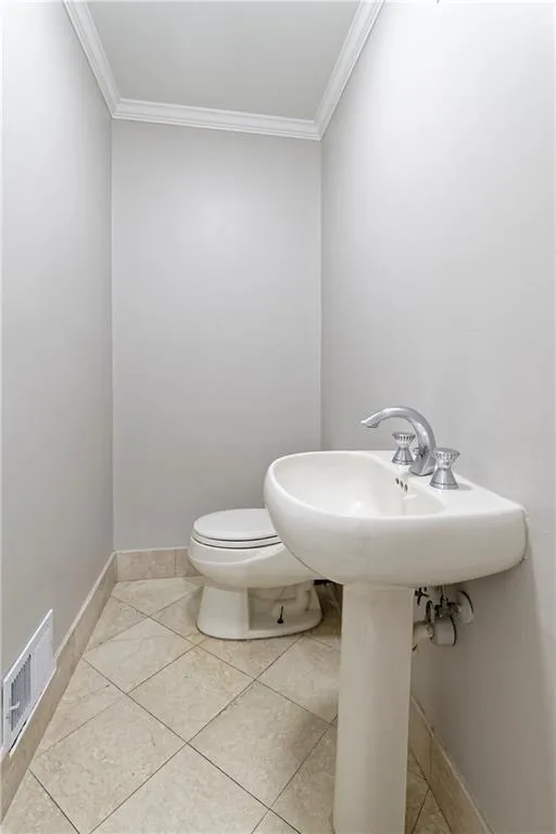 Bathroom with crown molding, toilet, and tile patterned floors