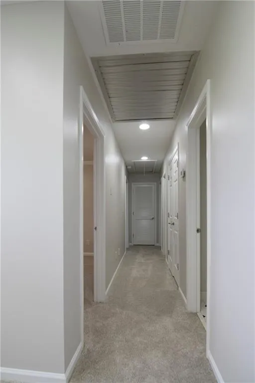 Hall featuring attic access, carpet, and baseboards