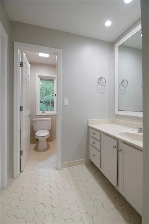 Bathroom with toilet, vanity, and baseboards