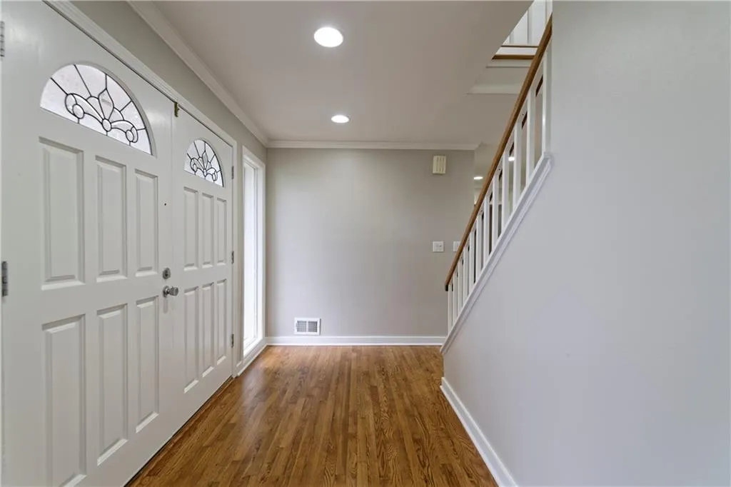 Foyer featuring crown molding, baseboards, wood finished floors, recessed lighting, and stairway