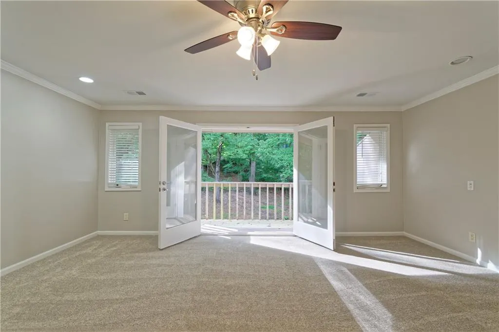 Unfurnished room with carpet, baseboards, plenty of natural light, crown molding, and a ceiling fan