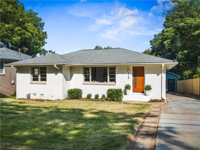 White painted brick exterior with a gray shingle roof & MCM-inspired front door.