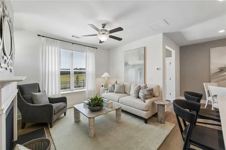 Living space featuring wood-finish flooring, a ceiling fan with integrated lighting, and a white mantel