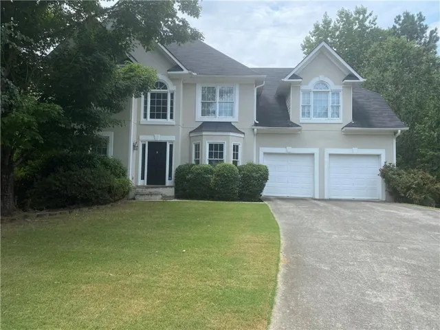 Stucco exterior featuring a two-story design and arched window accents
