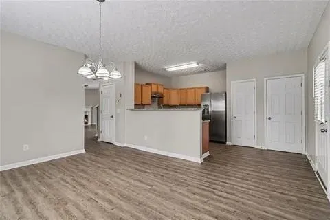 Open-concept living area featuring wood-finish flooring, a contemporary chandelier, and light gray wall paint